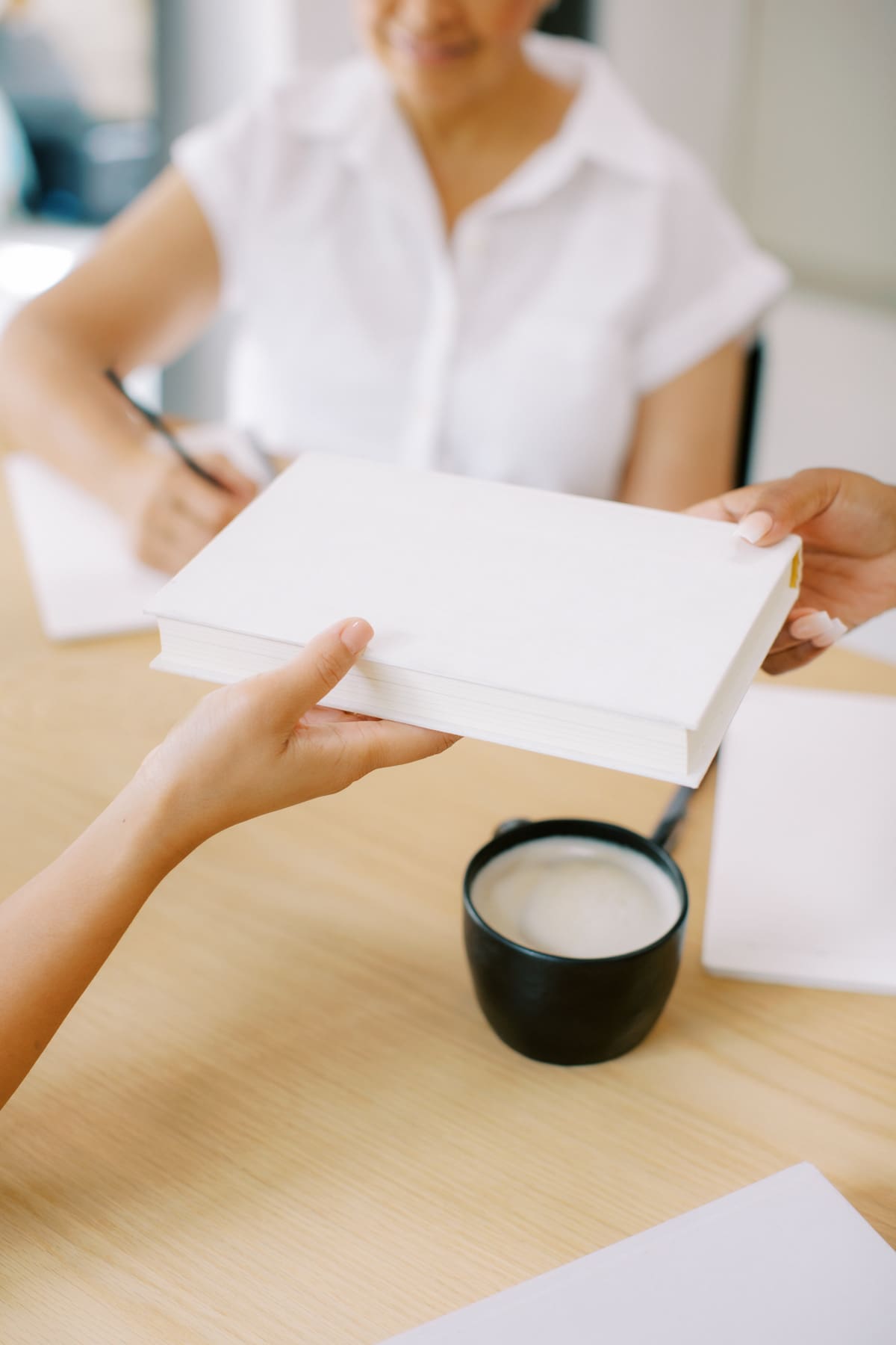 Woman at work handing a document to a colleague and delegating a task instead of taking it all on herself